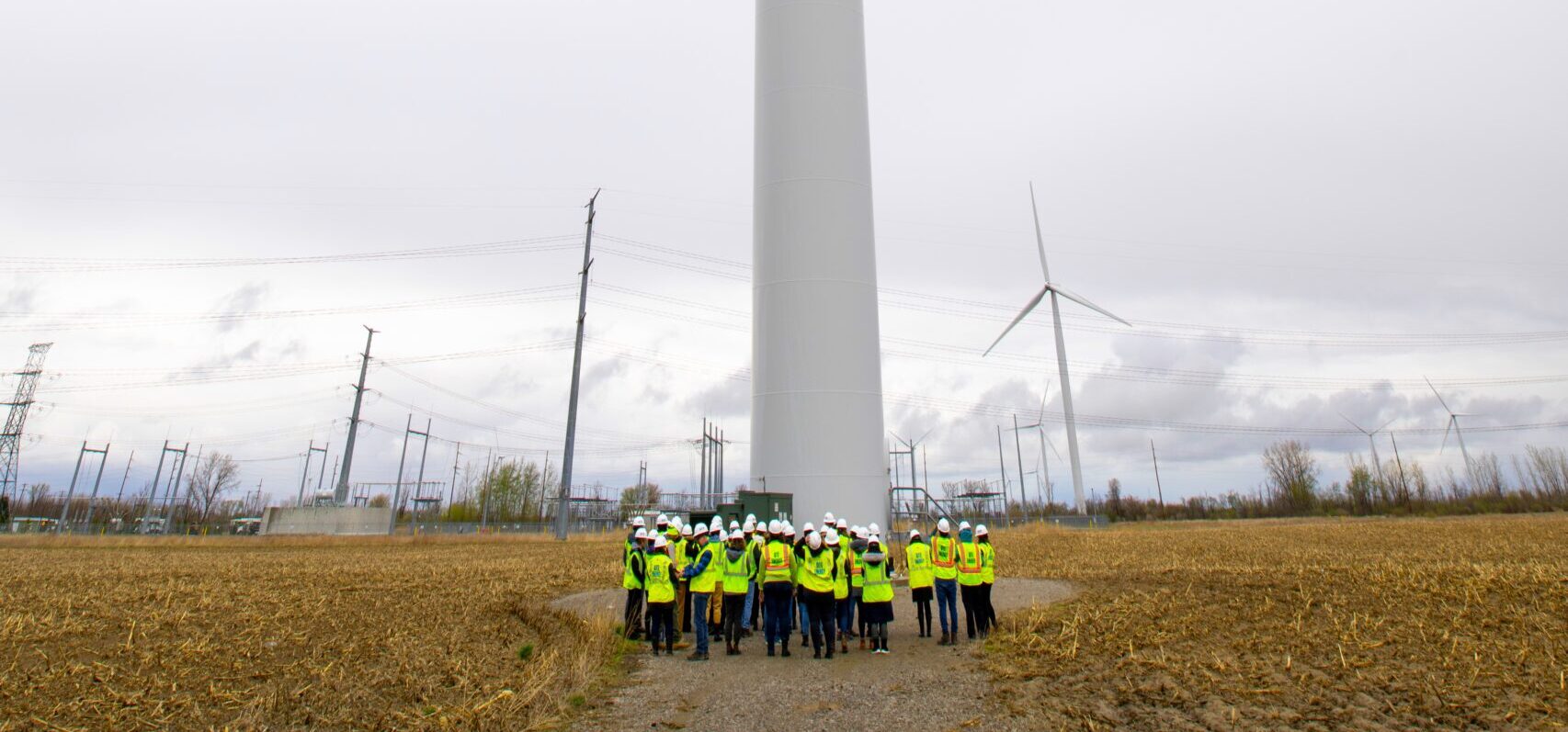 Group of people gather around large windmill