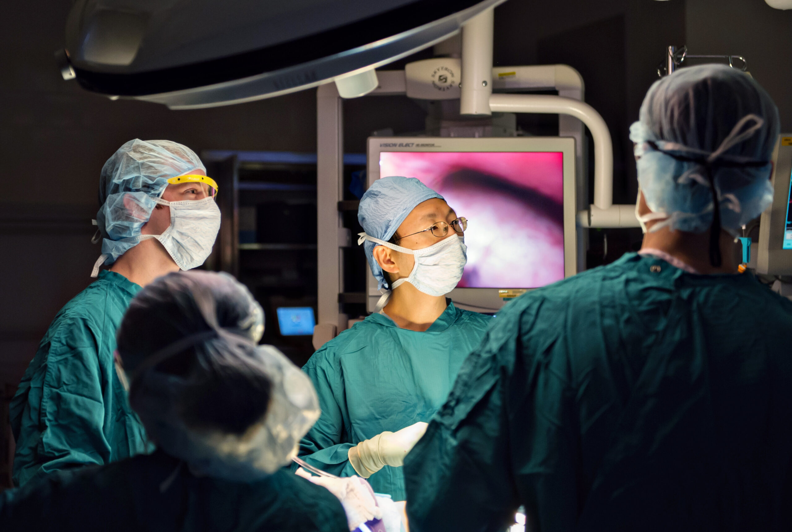 Doctors in scrubs in operating room examine screen