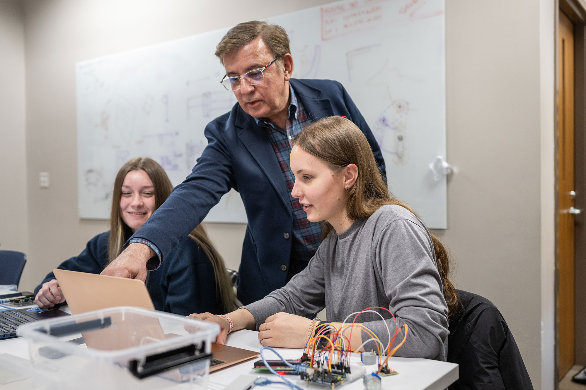 Kas Kasravi (center), lecturer III in industrial and manufacturing systems at UM-Dearborn, helps students in his prototype-design lab use AI to write code to create microcontrollers.