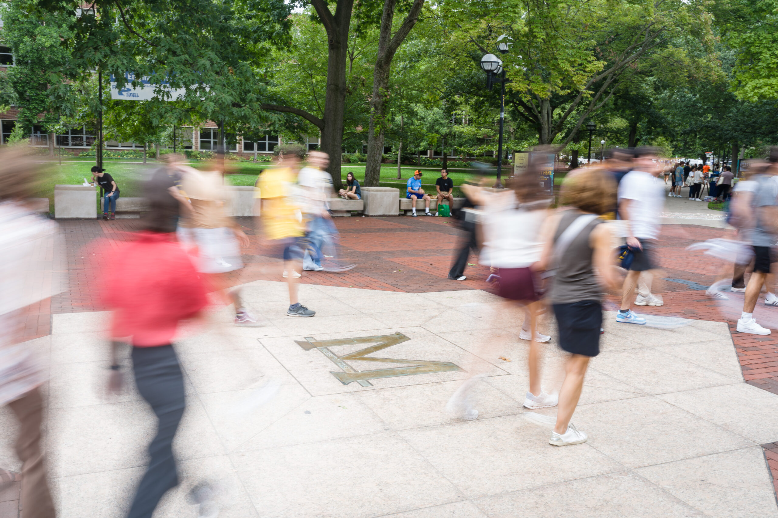 Blurred photo of groups of students walking through campus public space