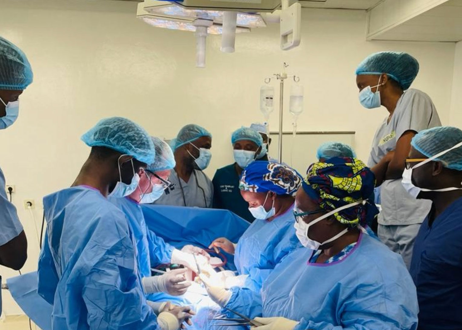 Jeffrey Punch, third from left, works with a trainee on a kidney transplant as other team members and students observe. At the head of the table observing are, at left, Lloyd Brown, a transplant surgeon from Rush University, and, at right, Sabin Nsanzimana, Rwanda’s minister of health.