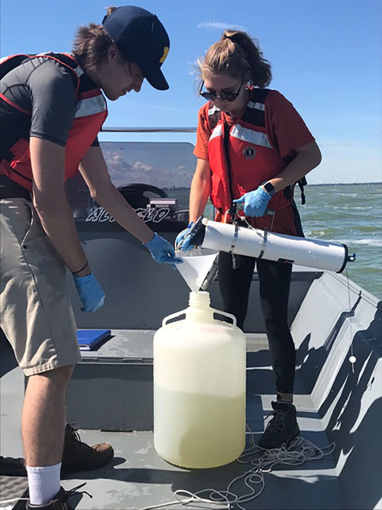 Former U-M students Claire Zwiers and Derek Smith collect water samples from a cyanobacterial harmful algal bloom in western Lake Erie in September 2019. The fieldwork was part of a project, funded by the National Science Foundation and the Great Lakes Center for Fresh Waters and Human Health, to study the effect of environmental conditions on toxin production by cyanobacteria.